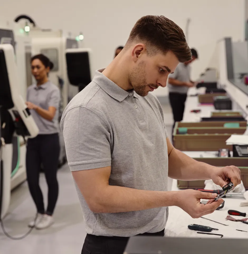 White caucasian man on an assembly line in a factory looking at a part seriously